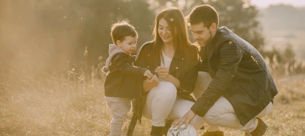 A cheerful family bonding outdoors with a soccer ball, enjoying a sunny day in the grass.